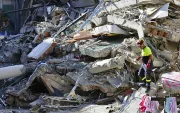 Un integrante de organismos de socorro camina sobre los escombros de una edificación destruida tras el terremoto de magnitud 7,4 que sacudió la víspera la mayor parte de Colombia, este martes en Pereira (Colombia).