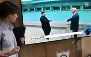 Una mujer pasa junto a una pantalla de televisión que muestra reunión entre el presidente Donald Trump y el líder norcoreano Kim Jong Un, en estación de tren de Seúl.