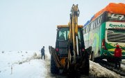 Operarios trabajando con maquinaria amarilla para limpiar una carretera durante una nevada en La Paz (Bolivia).