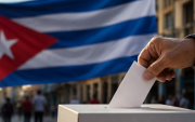 Una persona deposita su voto en una urna, con la bandera de Cuba de fondo, en una representación sobre el debate en torno al sistema electoral de la isla.