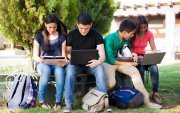 Group of teenagers social networking using several tech devices in high school