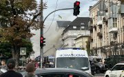 Personas observan cómo rescatistas trabajan para extinguir un incendio tras un ataque aéreo en Kiev.