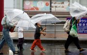 Personas se cubren de las lluvias causadas por el tifón Dujuan en Tokio, Japón.