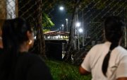 Unas mujeres miran a través de una valla durante una vigilia para exigir la liberación de los presos políticos venezolanos frente a la prisión El Rodeo I en Guatire.