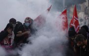 Estudiantes de secundaria permanecen en medio de gases lacrimógenos mientras estallan enfrentamientos entre estudiantes y la policía antidisturbios.