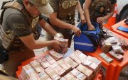 Integrantes de la Fuerza Especial de Lucha Contra el Crimen (FELCC) de Bolivia cuentan billetes que fueron encontrados en una ambulancia.