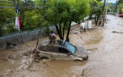 Una persona se refugia sobre un vehículo afectado por un aluvión, el jueves 8 de octubre de 2026, en la comuna de Las Condes, en Santiago de Chile.