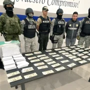 Agentes de Policía y Aduana exhiben el dinero y paquetes incautados durante el operativo en Quito.