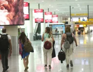 Personal aeroportuario y viajeros se movilizan hacia la terminal aérea con documentación de vuelo en medio de las restricciones nocturnas.