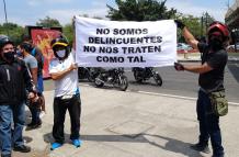 Dos motociclistas sostienen un cartel en el que piden no ser tratados como delincuentes.