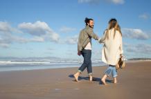 side-view-of-caucasian-couple-on-summer-vacation-bearded-man-and-woman-in-casual-clothes-walking-on-beach-holding-hands-love-travelling-tenderness-concept