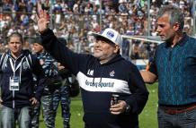 La estrella del fútbol argentino Diego Maradona saluda al público junto al presidente Gabriel Pellegrino.