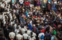 Migrantes hondureños se arrodillan para orar frente a los policías guatemaltecos, el 17 de enero de 2021 desde la aldea Vado Hondo, Chiquimula (Guatemala).