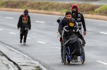Ciudadanos venezolanos, uno de ellos con discapacidad, transitan por una carretera cercana a Quito (Ecuador).