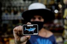 Una turista muestra un imán con la imagen de un tiburón, el 12 de agosto de 2021, en Jaboatao dos Guararapes (Brasil).