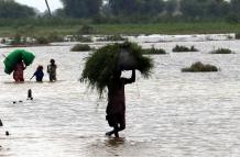 Varias personan vadean un área inundada tras las fuertes lluvias en Sanghar, Pakistán, el 23 de agosto de 2022.