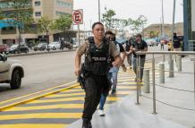 Policías persiguen hoy a un presunto delincuente a pocas cuadras de la sede del canal de televisión TC, donde encapuchados armados ingresaron y sometieron a su personal durante una transmisión en vivo, en Guayaquil