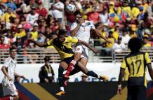 El defensor venezolano Yordan Osorio se dirige contra el delantero ecuatoriano Kevin Rodríguez