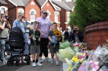 Dos niños depositan flores en el lugar del apuñalamiento múltiple registrado en Southport, Gran Bretaña, el 30 de julio de 2024.