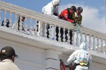 Agentes de la Policía y socorristas de los Bomberos de Cayambe trabajaron para rescatar al hombre que las personas dejaron suspendido en el atril del edificio del Municipio de Cayambe.