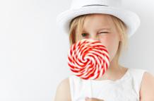 little-blonde-girl-wearing-white-hat-holding-sugar-candy