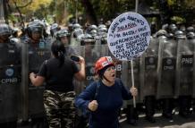Personas se manifiestan durante una protesta frente a miembros de la Policía Nacional Bolivariana (PNB)