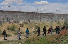 Migrantes caminan cerca del muro que separa la frontera estadounidense en Ciudad Juárez, Chihuahua (México).