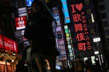 Personas caminando por una calle junto al letrero de neón "I love Kabukicho" en la zona de entretenimiento del distrito rojo