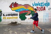 Fotografía del 2 de abril del 2025 de una persona caminando frente a un mural con el mapa de Venezuela en Caracas (Venezuela).