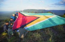 hombres desplegando una bandera de Guyana en la montaña Pakrampa, en la aldea de Arau, región Esequibo (Guyana).