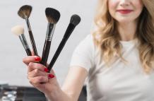sonriendo-visagiste-mujer-sosteniendo-cepillos-cosmeticos