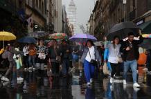 Personas se protegen de la lluvia con sombrillas en México