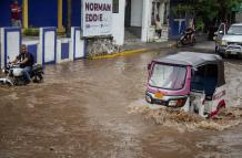 Conductor de moto taxi que circula por una calle inundada