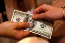Dos manos sosteniendo un billete que puede interpretarse como recibo de remesas