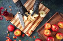vista-superior-cocinera-cortando-manzanas-en-la-superficie-gris