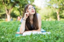 mujer-hermosa-joven-se-acuesta-en-campo-verde-y-lee-el-libro