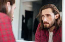 hombre-en-camisa-cuadros-mirando-al-espejo-en-casa