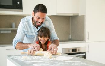 joyful-happy-dad-and-his-girl-enjoying-time-together-while-rolling-and-kneading-dough-in-kitchen