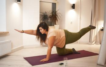 sid-view-of-overweight-obese-young-woman-wearing-t-shirt-and-leggings-doing-physical-training-on-mat-to-strengthen-legs-arms-abs-and-spine-weght-loss-fitness-sports-and-active-lifestyle-concept