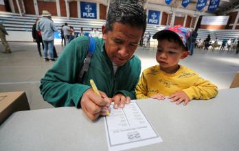 Un ciudadano venezolano residente en Ecuador fue registrado este domingo, 22 de octubre, al votar, junto a un niño, en las elecciones primarias de la oposición, en Quito (Ecuador).