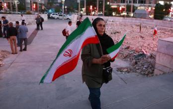 Una mujer iraní con banderas nacionales escucha a una banda de música tradicional que toca en solidaridad con el pueblo iraní en la plaza Hafte-Tir, en el centro de Teherán, Irán, el 23 de junio de 2025.