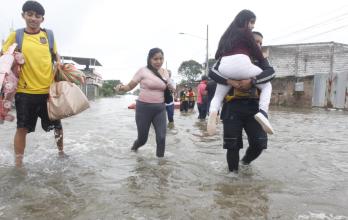 padres cargando niños en calles inundadas de Milagro