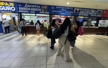 Pasajeros revisan horarios en la Terminal Terrestre de Guayaquil tras cambios por el toque de queda en Guayas.