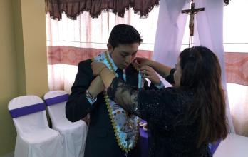 Los padres inculcan la fe en los jóvenes que participan en el arrastre de las banderas en Viernes Santo.