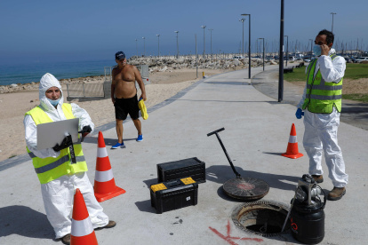 ASHKELON. Técnicos de la firma israelí Kando extraen muestras de aguas residuales de una boca de inspección cerca de la playa de esta ciudad balnerario.