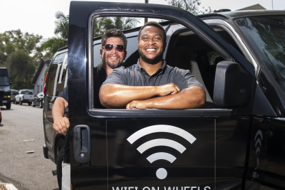 Roman Reyna (L) owner of JFK transportation and Kevin Watson (R), president of JFK transportation, pose with one of their company vans equipped as a mobile Wifi Hotspot to help students access internet to remotely attend their classes, September 16, 2020, in Santa Ana, California. - A minivan with a Wi-fi router attached to the dashboard and a satellite antenna on the roof is helping 200 disadvantaged students in Santa Ana, close to Los Angeles, cope with the rigors of distance learning during the coronavirus pandemic. (Photo by VALERIE MACON / AFP)