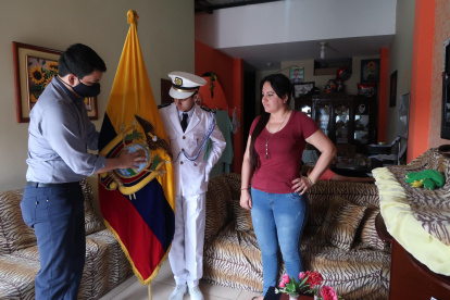 Anthony Santillán Mora, abanderado de la Academia Naval Guayaquil, recibe en su casa la bandera por parte de un directivo de la plantel. A su lado está su mamá.