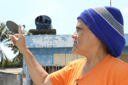 Janeth Maenza muestra su tanque de agua derretido por el calor. Su casa está a seis metros del incendio.
