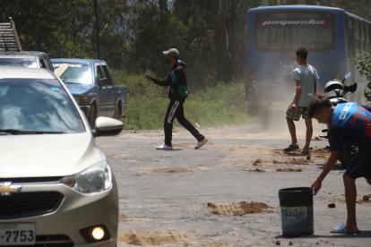 Los extranjeros aprovechan los enormes baches en la vía para rellenarlos y ganar algo de dinero.