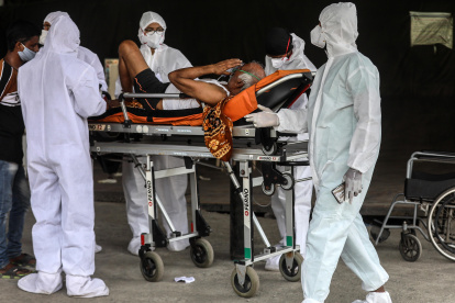 Los trabajadores sanitarios atienden a un paciente sospechoso de covid-19 que espera fuera del centro de salud Covid-19 en Mumbai, India, el 19 de abril de 2021.